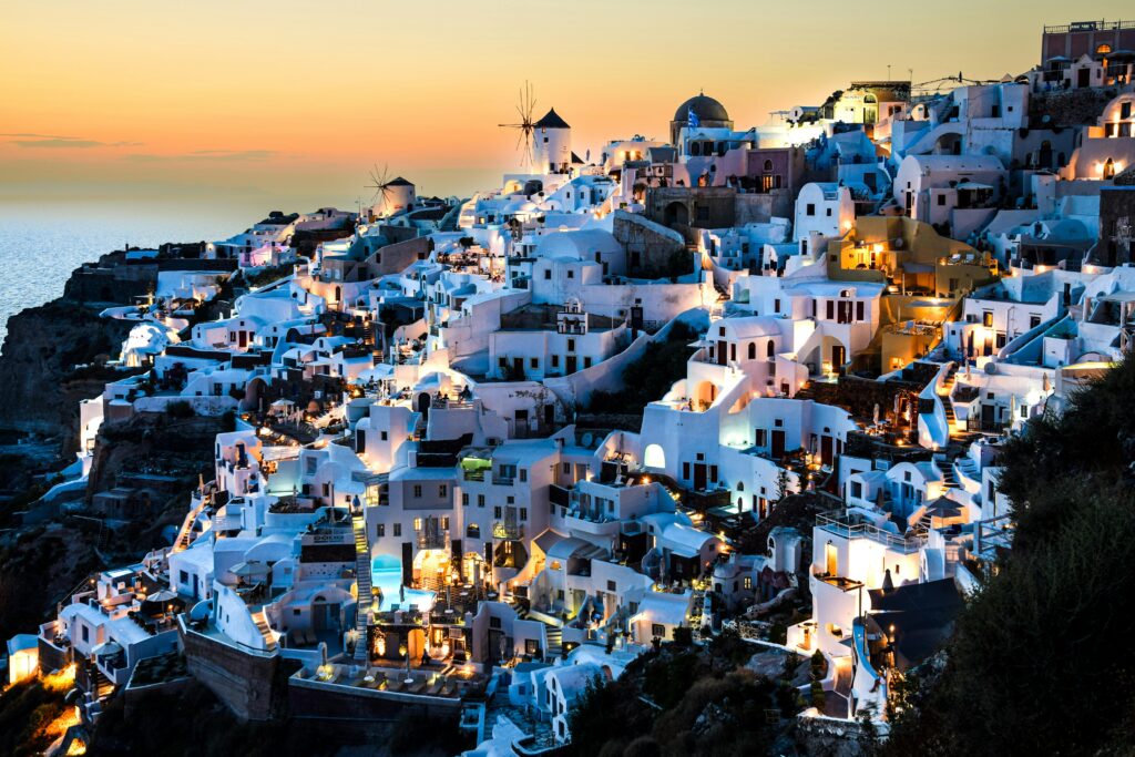 Explore the stunning view of Oia, Santorini, with illuminated white buildings at twilight.